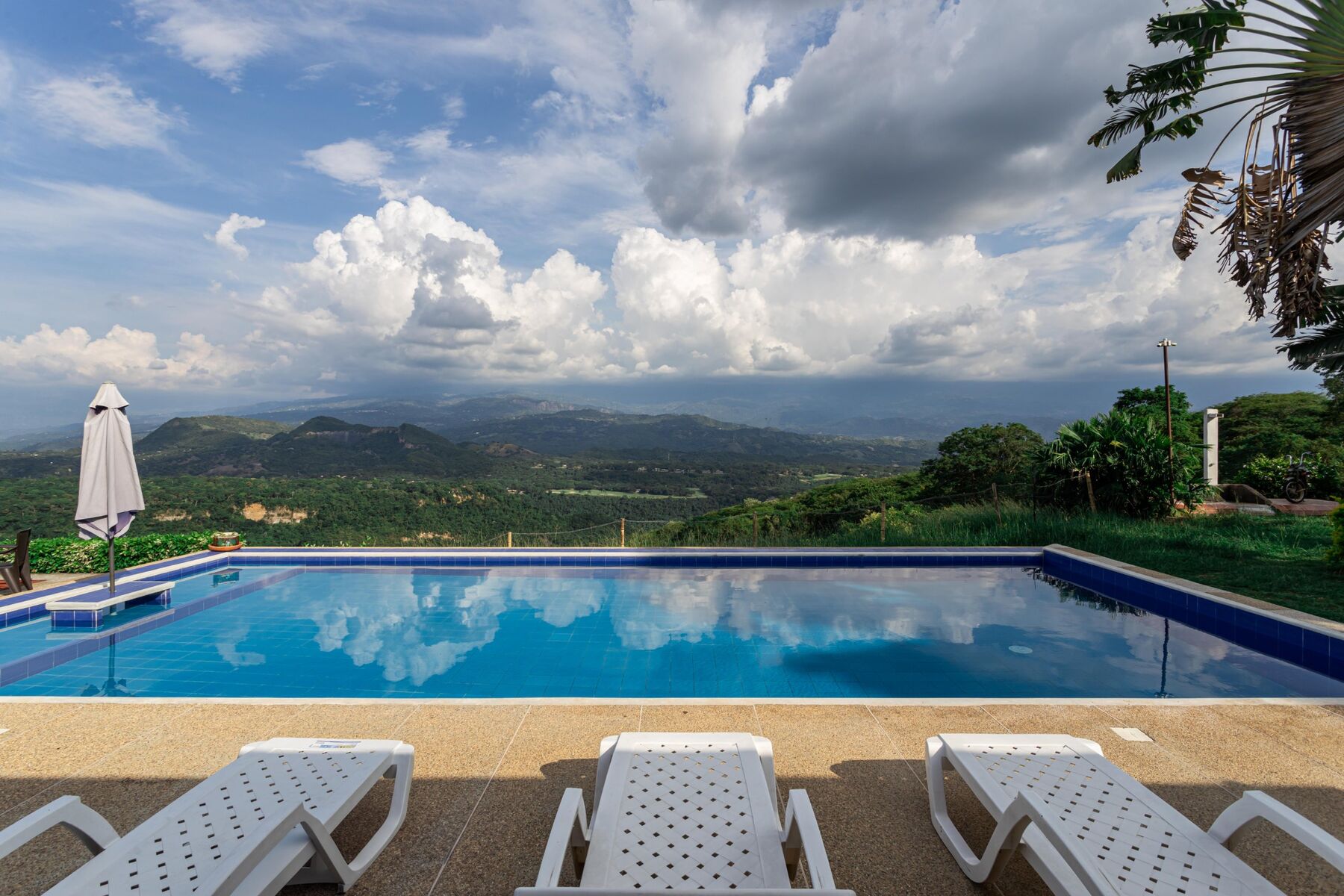 Piscina de El Encanto reflejando las nubes, con vista abierta al valle